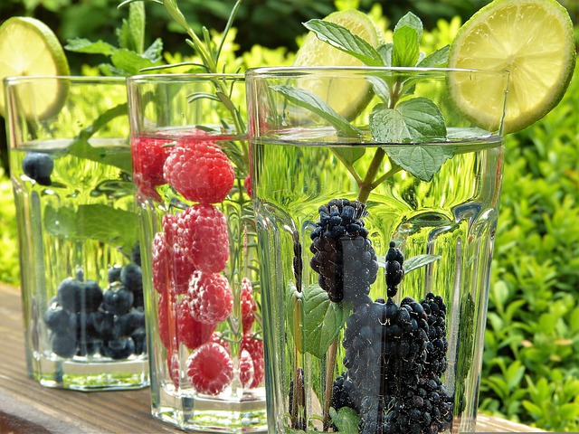 Three glasses of water with fresh berries and citrus